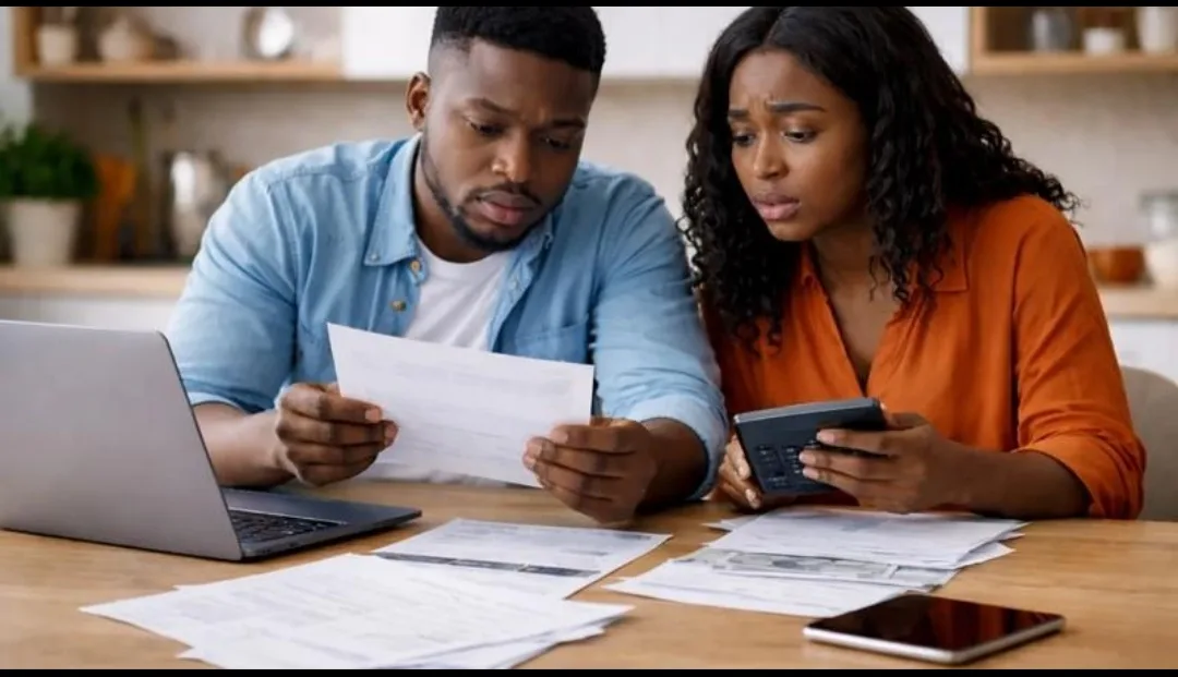 An African couple reviews household bills and calculates expenses to manage their monthly financial commitments.
